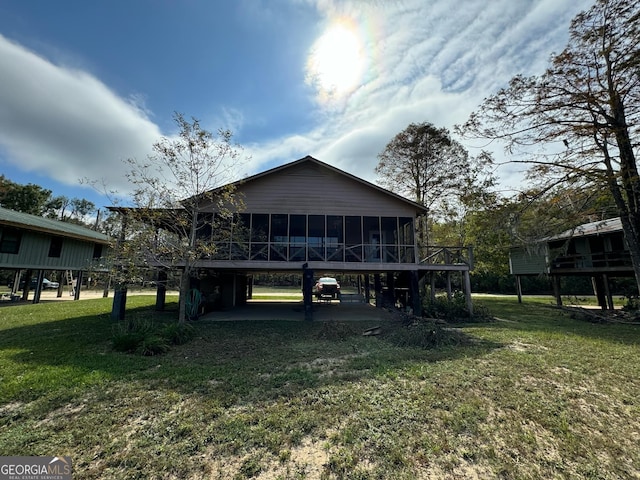 back of property featuring a yard, a carport, and a sunroom