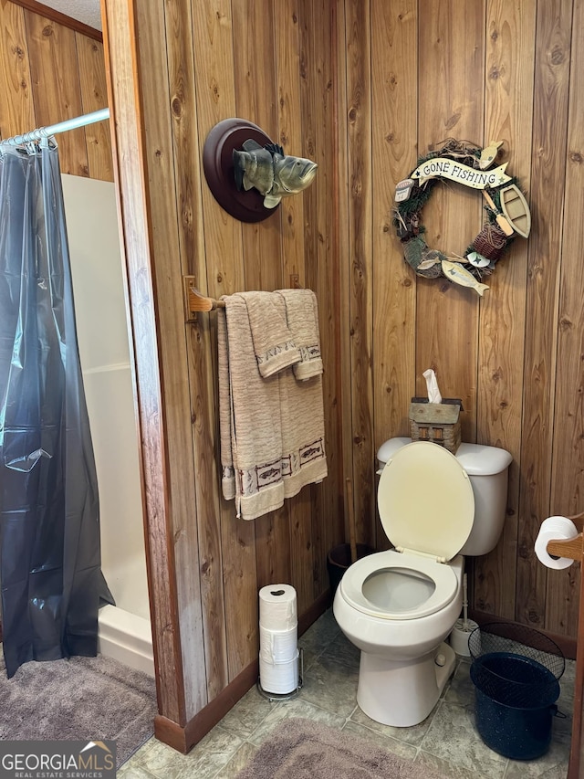 bathroom with tile patterned floors, wood walls, and toilet