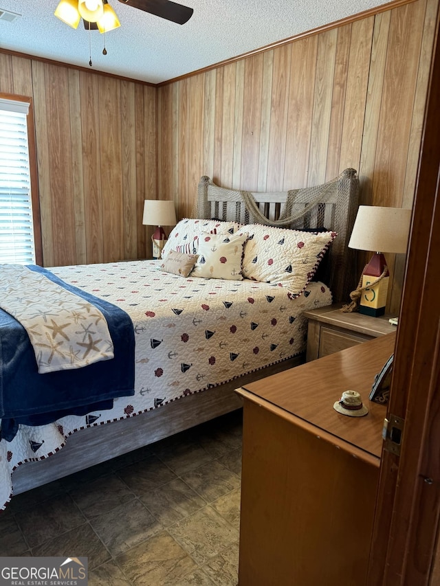 bedroom with ceiling fan, a textured ceiling, and wooden walls