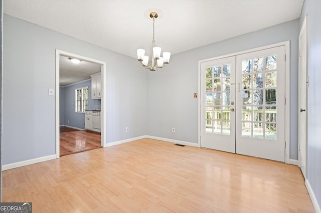 interior space featuring a textured ceiling, light hardwood / wood-style floors, and a notable chandelier