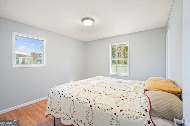 bedroom featuring wood-type flooring, a textured ceiling, and multiple windows