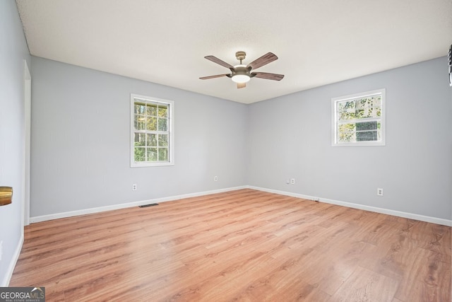 empty room featuring light hardwood / wood-style flooring, ceiling fan, and a healthy amount of sunlight