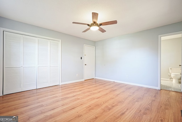 unfurnished bedroom featuring ceiling fan, light hardwood / wood-style floors, a closet, and ensuite bath