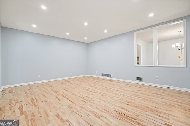 empty room with light hardwood / wood-style floors and a notable chandelier