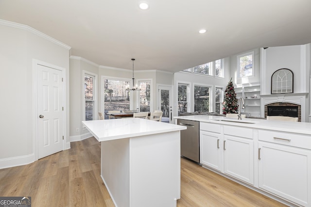 kitchen featuring sink, light hardwood / wood-style flooring, dishwasher, hanging light fixtures, and an island with sink