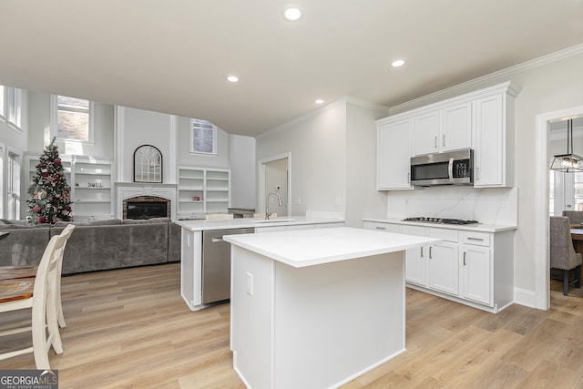 kitchen with light wood-type flooring, stainless steel appliances, white cabinetry, and sink