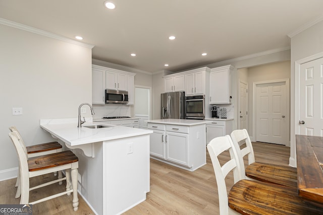 kitchen featuring kitchen peninsula, white cabinetry, sink, and appliances with stainless steel finishes