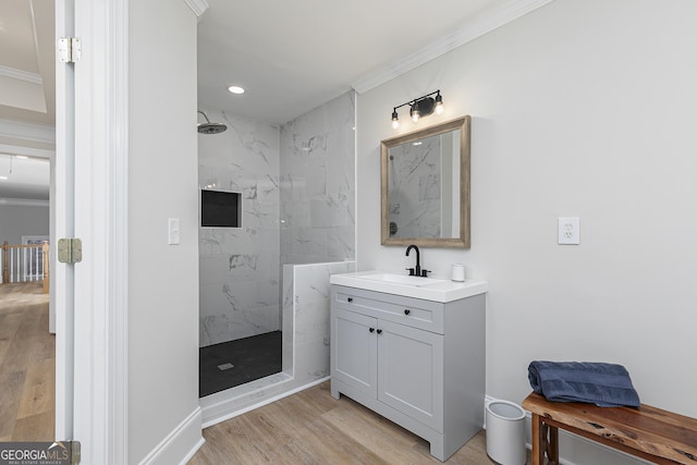 bathroom with tiled shower, hardwood / wood-style floors, vanity, and crown molding