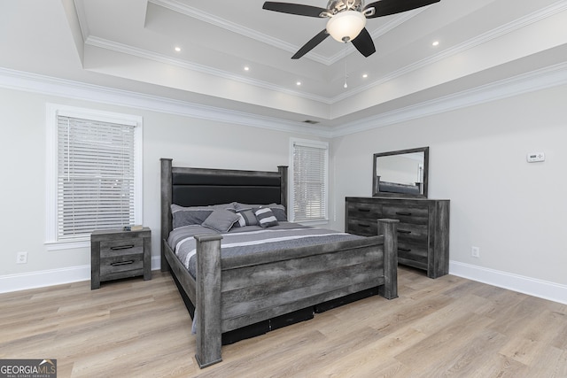 bedroom with a raised ceiling, ceiling fan, light wood-type flooring, and ornamental molding