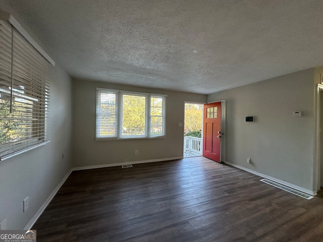 empty room with a textured ceiling and dark wood-type flooring