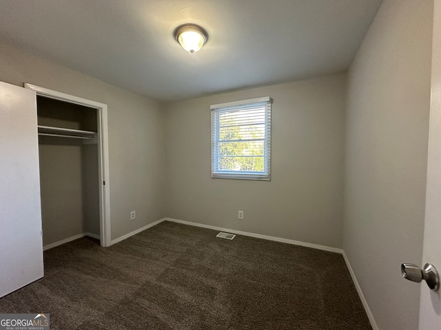 unfurnished bedroom with a closet and dark colored carpet