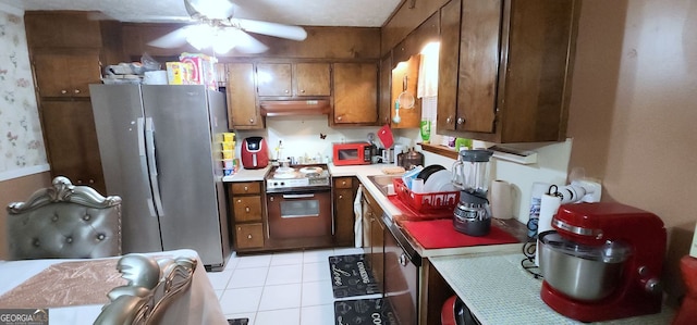 kitchen with ceiling fan, light tile patterned floors, a textured ceiling, appliances with stainless steel finishes, and extractor fan