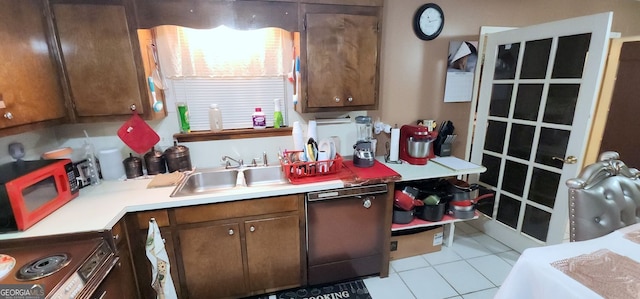 kitchen featuring light tile patterned floors, dark brown cabinetry, stainless steel dishwasher, and sink