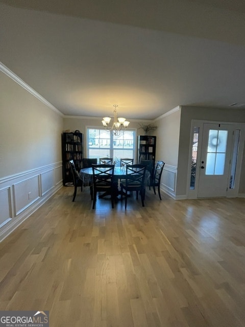 dining space with crown molding, an inviting chandelier, and hardwood / wood-style flooring