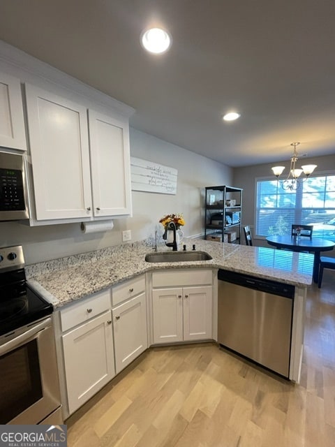 kitchen featuring an inviting chandelier, white cabinets, sink, light hardwood / wood-style flooring, and appliances with stainless steel finishes