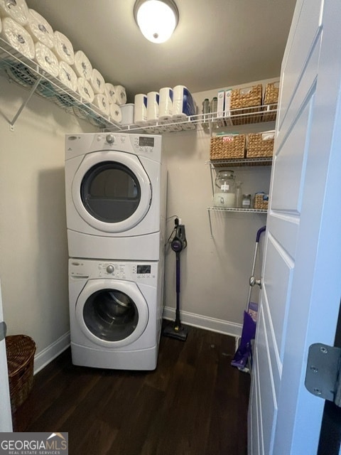 clothes washing area featuring stacked washer / dryer and dark wood-type flooring