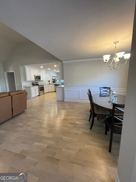 dining space with light hardwood / wood-style floors, crown molding, and a notable chandelier