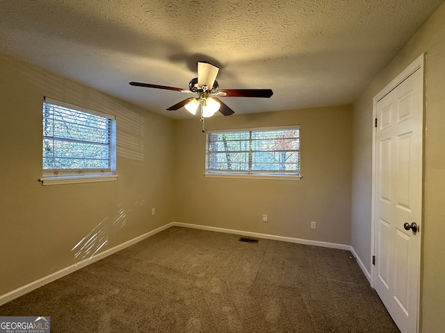 unfurnished bedroom featuring dark colored carpet, ceiling fan, and multiple windows