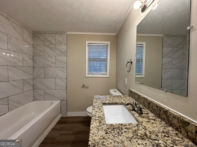 full bathroom with hardwood / wood-style floors, tiled shower / bath, toilet, ornamental molding, and a textured ceiling