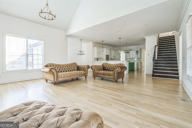 living room featuring a notable chandelier, lofted ceiling, and light hardwood / wood-style flooring