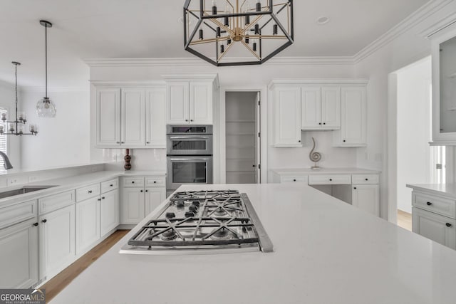 kitchen with white cabinets, pendant lighting, sink, and appliances with stainless steel finishes