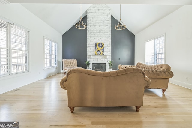 living room with light hardwood / wood-style floors, a brick fireplace, and plenty of natural light