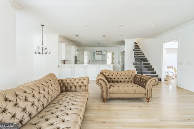 living room featuring light hardwood / wood-style floors, sink, crown molding, and an inviting chandelier