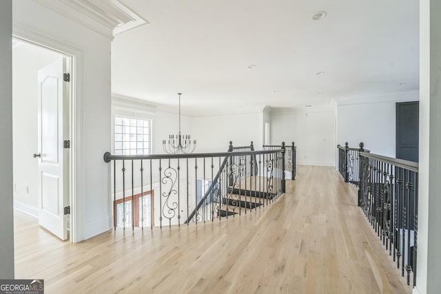 hallway featuring light wood-type flooring, an inviting chandelier, and crown molding