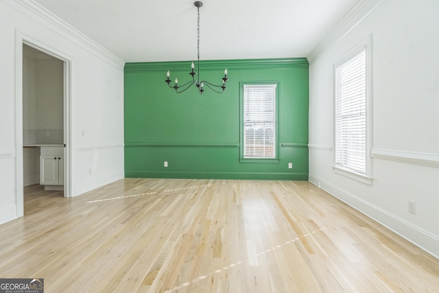 spare room featuring plenty of natural light, light hardwood / wood-style floors, and ornamental molding