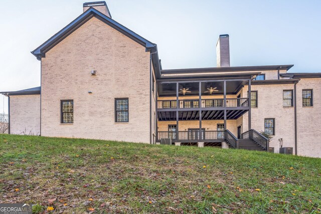 rear view of property featuring a lawn and a balcony