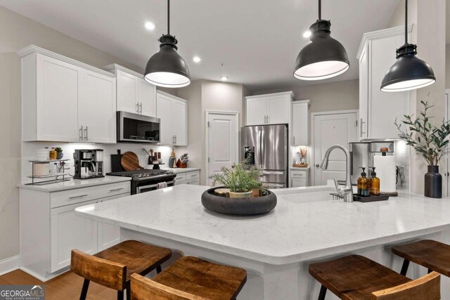 kitchen featuring sink, appliances with stainless steel finishes, white cabinetry, hanging light fixtures, and backsplash