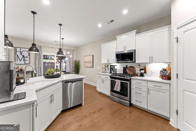 kitchen featuring sink, appliances with stainless steel finishes, white cabinets, pendant lighting, and backsplash