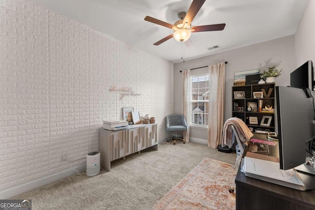 carpeted office with ceiling fan and brick wall