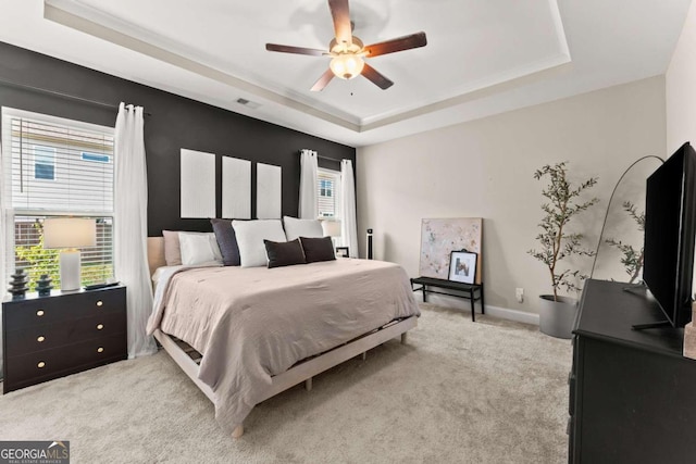 carpeted bedroom featuring ceiling fan and a tray ceiling