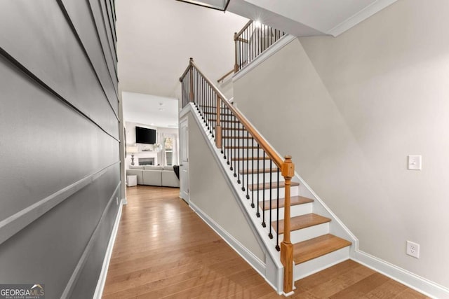 stairs featuring crown molding and hardwood / wood-style floors