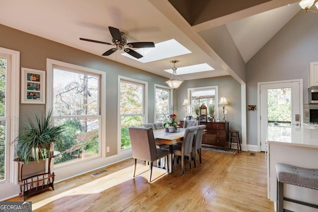 dining space featuring light hardwood / wood-style flooring, ceiling fan, and lofted ceiling with skylight