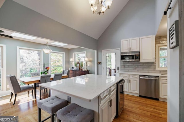 kitchen featuring decorative backsplash, a skylight, stainless steel appliances, white cabinetry, and a kitchen island