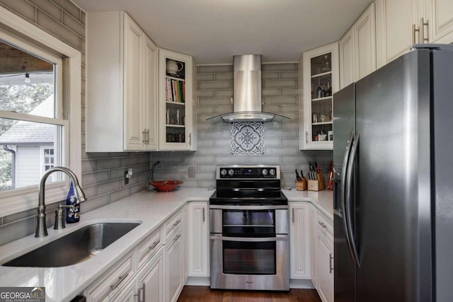 kitchen with white cabinets, appliances with stainless steel finishes, sink, and wall chimney range hood