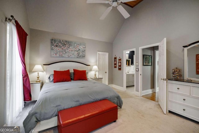 bedroom featuring ensuite bathroom, ceiling fan, light colored carpet, and high vaulted ceiling