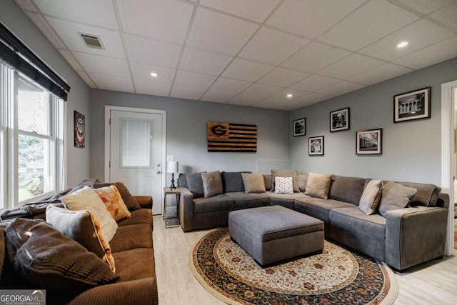 living room with light wood-type flooring and a paneled ceiling