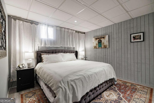 bedroom featuring wood walls and coffered ceiling