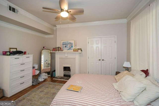 bedroom featuring a closet, crown molding, dark hardwood / wood-style flooring, and ceiling fan