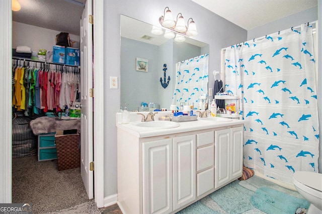 bathroom with vanity, curtained shower, toilet, and a textured ceiling