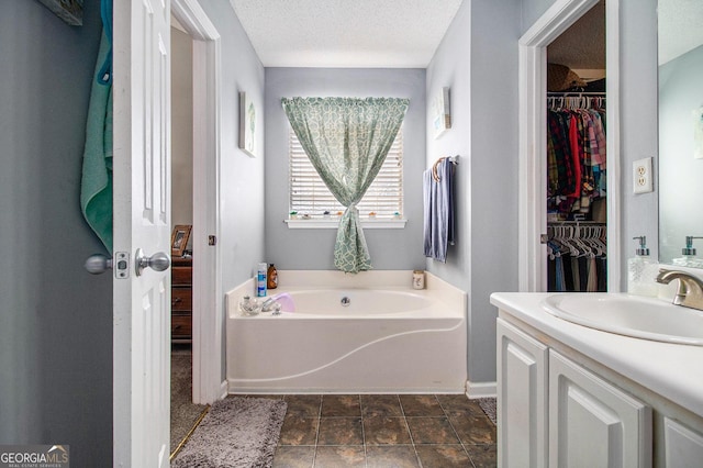 bathroom with vanity, a bath, and a textured ceiling