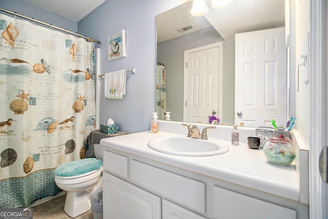 bathroom with tile patterned floors, vanity, a textured ceiling, and toilet