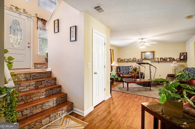 stairway featuring hardwood / wood-style floors, a textured ceiling, and ceiling fan