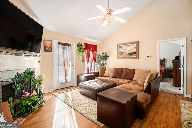 living room featuring hardwood / wood-style flooring, ceiling fan, high vaulted ceiling, and a brick fireplace