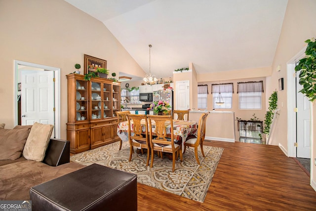 dining space featuring a notable chandelier, wood-type flooring, and high vaulted ceiling