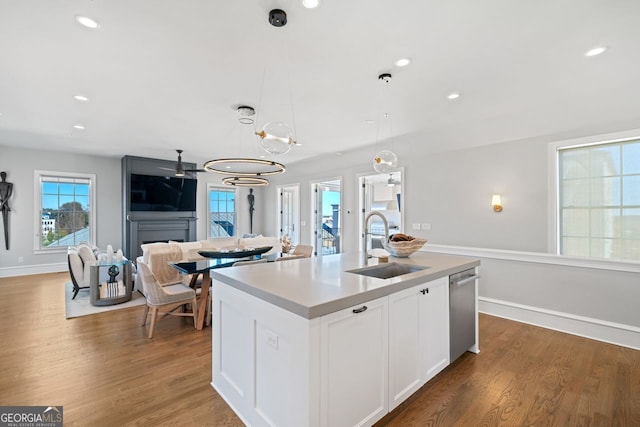 kitchen with white cabinetry, sink, dark hardwood / wood-style flooring, decorative light fixtures, and a center island with sink