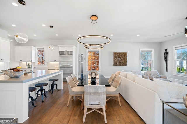 dining area with sink, dark wood-type flooring, and an inviting chandelier